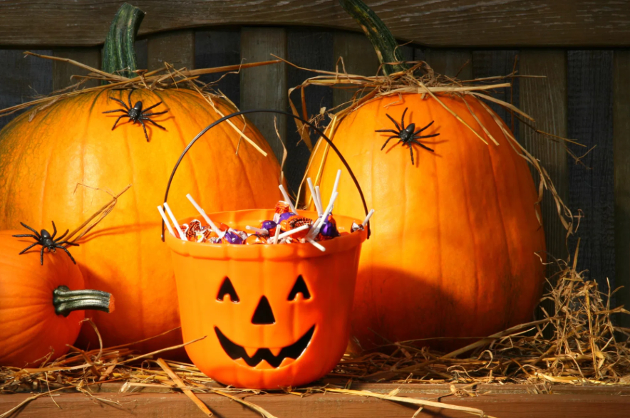 A bucket of Halloween candy with Halloween pumpkins.