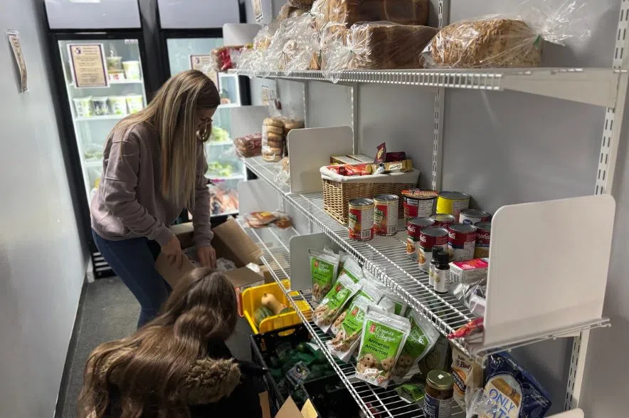 Volunteers sort food items on shelves inside the Al Ritchie Community Association food pantry.