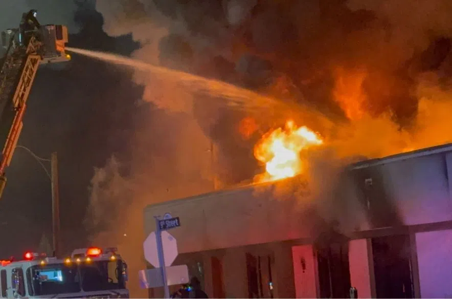 A Prince Albert fire truck extends an aerial ladder over the Salvation Army building as firefighters spray water onto flames breaking through the roof on Christmas night.