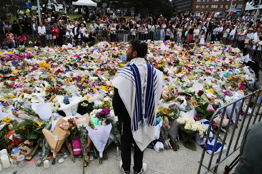 Rabbi Yossi Friedman speaks to people gathering at a flower memorial by the Bondi Pavilion at Bondi Beach on Tuesday, Dec. 16, 2025, following Sunday's shooting in Sydney, Australia.