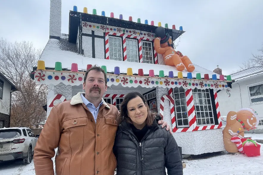 Tyson and Sharla Cote stand outside their home, which is decorated as a gingerbread house.