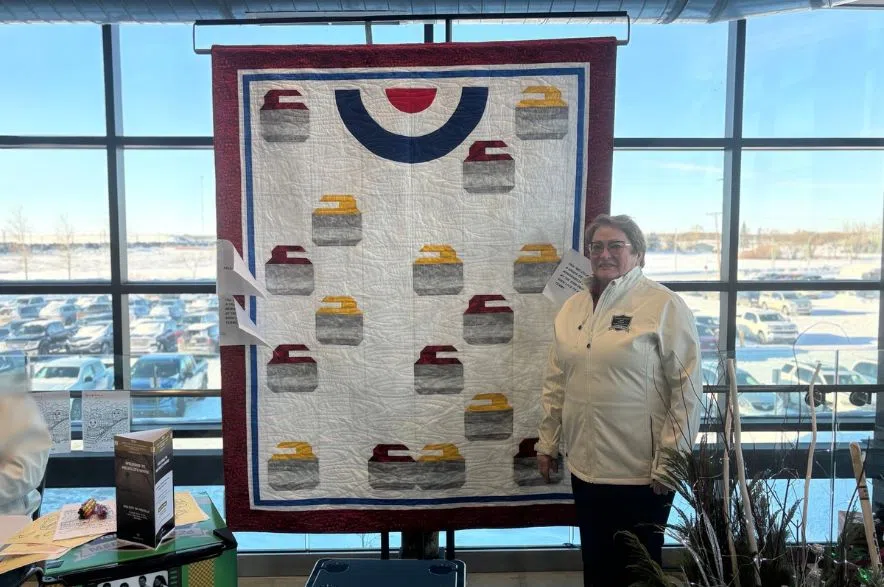 Betty Kotzer stands in front of a curling-themed quilt at Saskatchewan curling provincials.