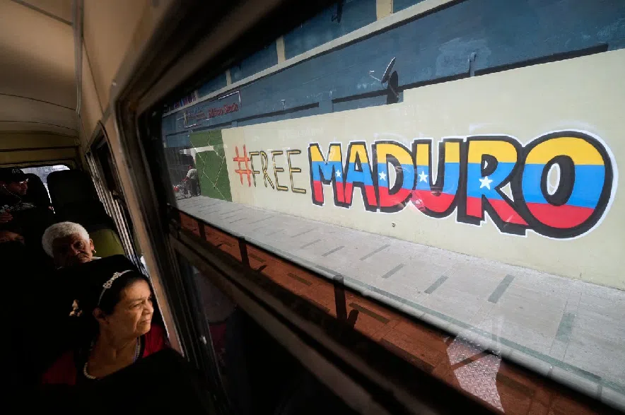 Commuters ride a bus past a mural calling for the release of former Venezuelan President Nicolas Maduro, who was detained by U.S. forces, in Caracas, Venezuela, Thursday, Jan. 8, 2026.