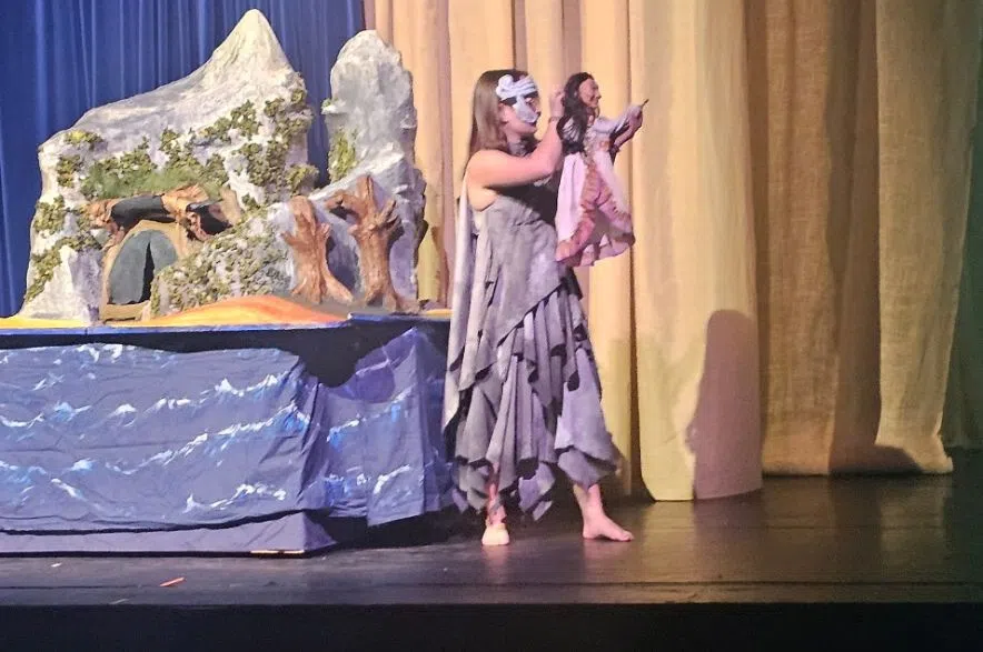 Performer holding puppet on stage during Deaf Tempest production Regina