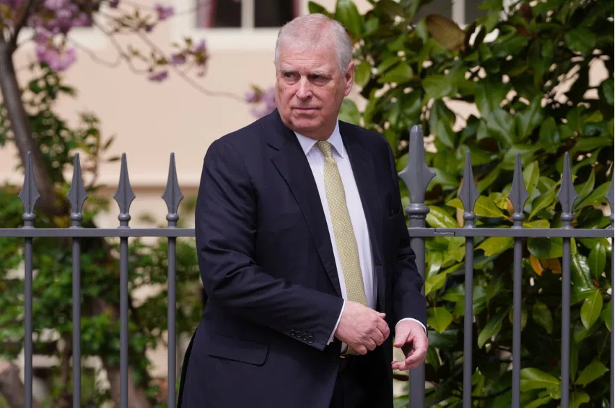 Former Prince Andrew stands in front of a gate.