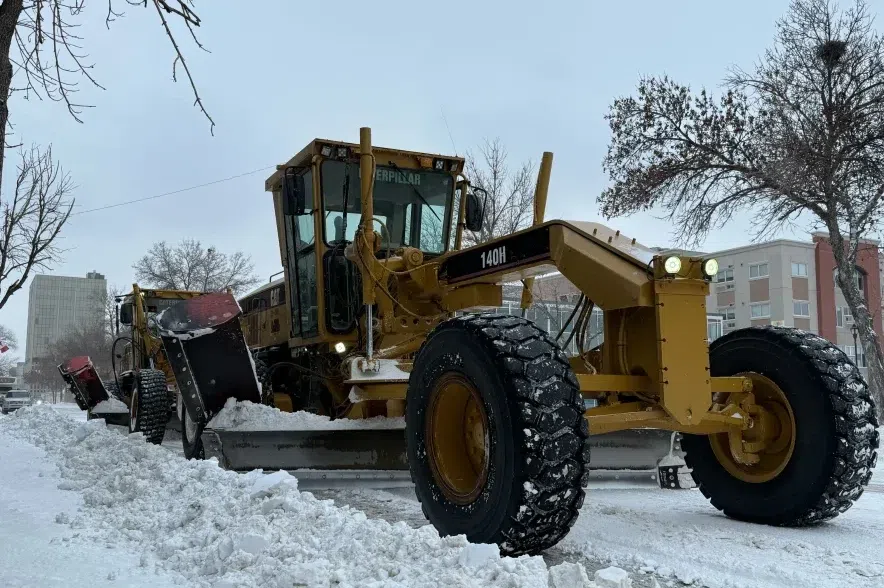 A large yellow snow grader on a Regina road clears snow to the side of the street.