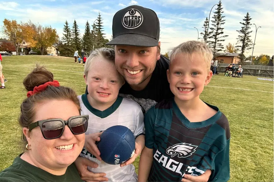Ashley Schwartz with her son Hayes, husband and other son posing for a photo in a park.