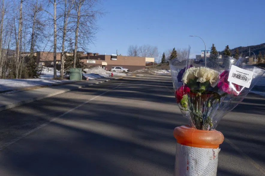 Flowers are placed in a barricade pylon on a road leading to Tumbler Ridge Secondary School in Tumbler Ridge, B.C., on Friday, Feb. 13, 2026.