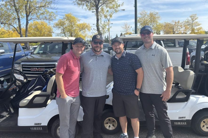 Brett Matchett and three other golfers standing beside golf carts at Joanne Goulet Golf Course.