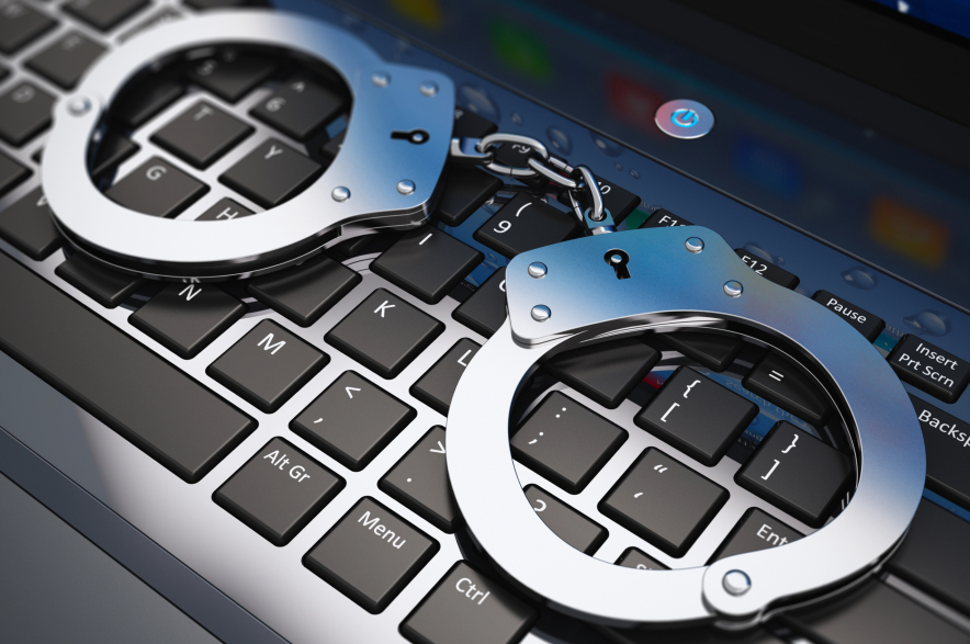 Metal handcuffs sit on a laptop.