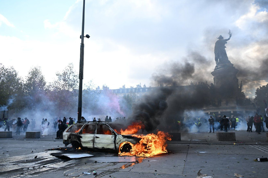 A car burns at Place de La Republique during a protest against rising living costs in Paris.