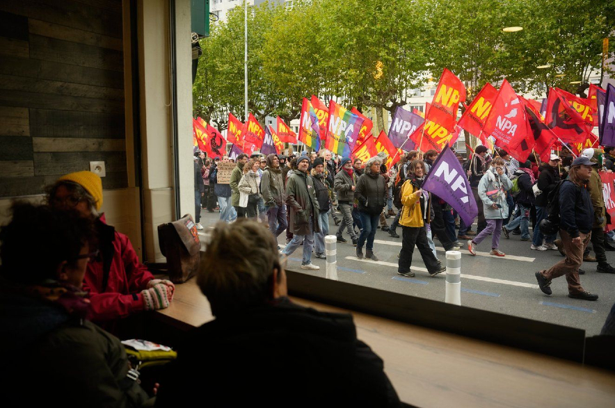 People sitting in a pub watch demonstrators during a protest in France.