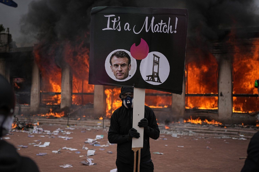 A protester holds a board with a photo of French president Emmanuel Macron.