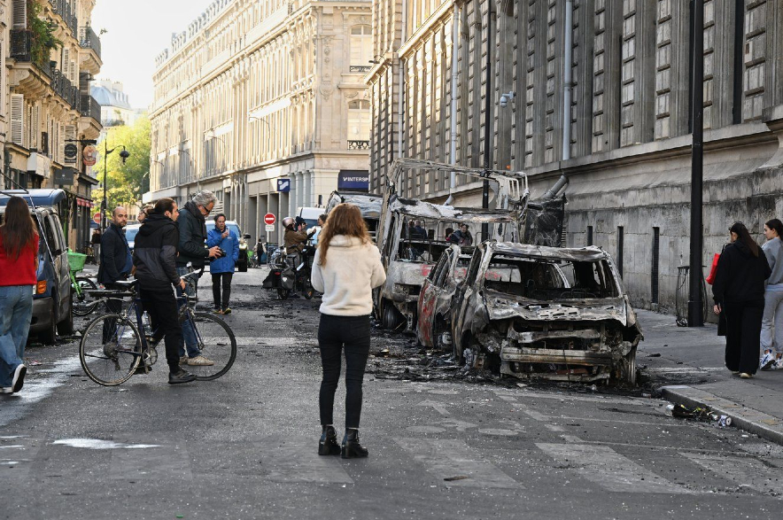 People look at charred cars the day after a demonstration in France.