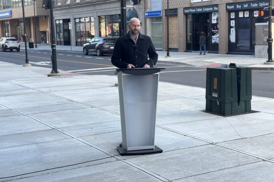 Regina deputy city manager Kurtis Doney speaks at a podium beside the newly reconstructed 11th Avenue in downtown Regina.