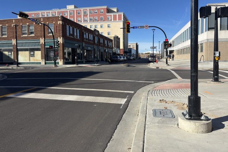 View down Smith Street showing fresh asphalt, new sidewalks, traffic lights and downtown Regina buildings.