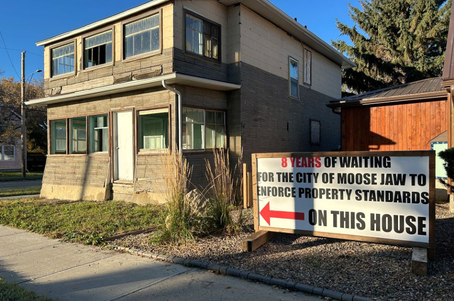 A sign erected by a neighbouring family calls on the City of Moose Jaw to enforce property standards.