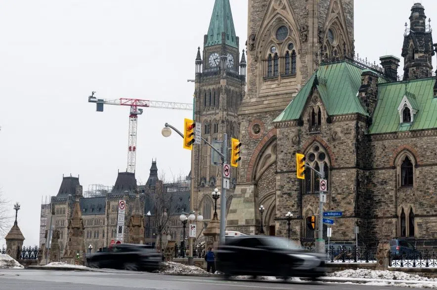 Vehicles make their way along Wellington St., in front of Parliament Hill in Ottawa, Monday, Dec. 16, 2024.