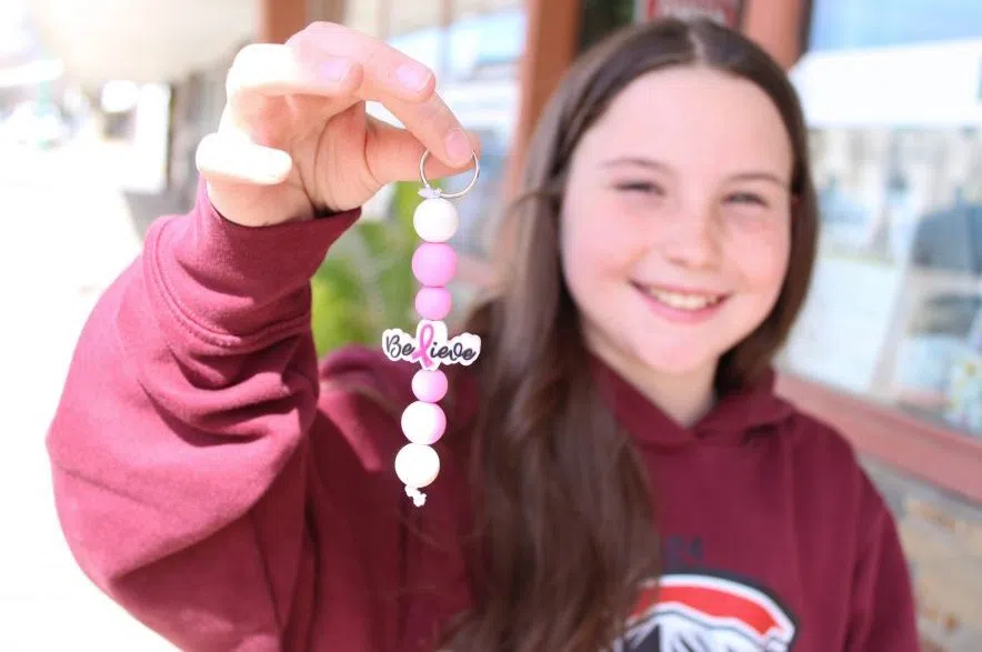 Lexi Curren holds a pink breast cancer awareness keychain in her outstretched hand