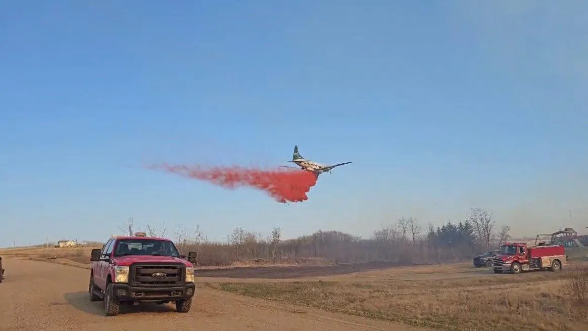 An air tanker drops fire retardant near a row of homes on James Smith Cree Nation as an uncontained wildfire burns nearby. (Melfort Fire & Rescue/Facebook)