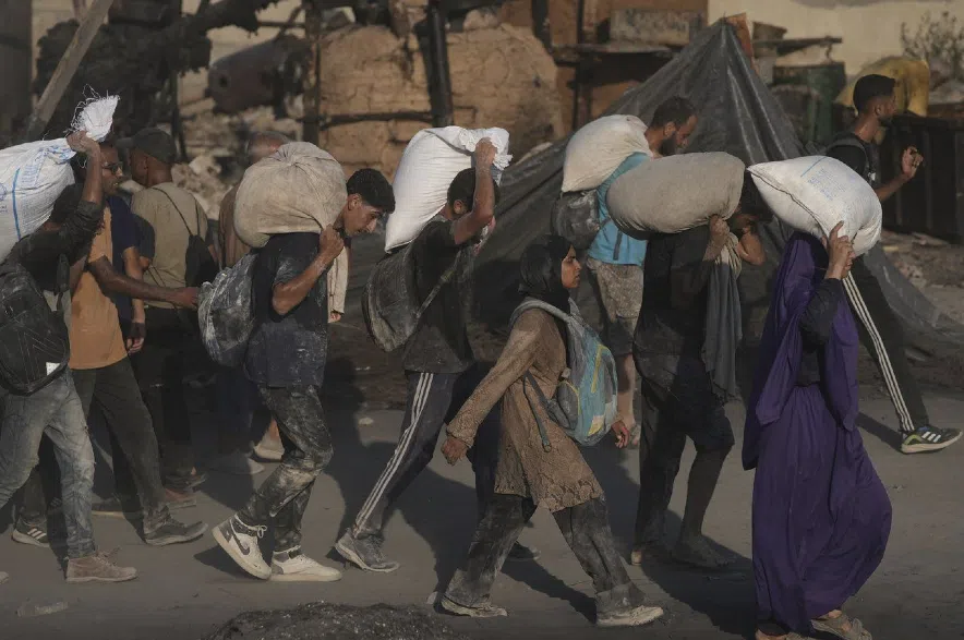 Palestinians carry sacks of flour.