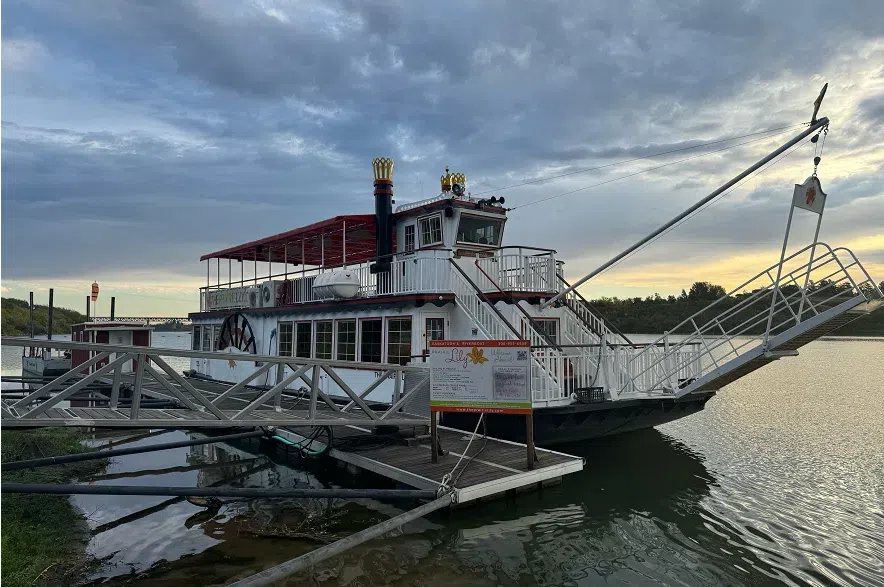 An old fashioned red and white boat docked on the river during sunset