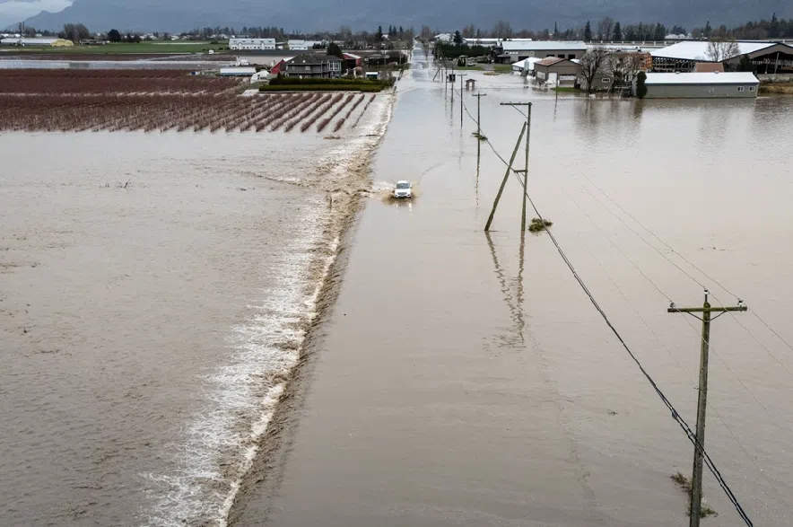A car crosses a flooded street in Abbotsford B.C., on Thursday, December 11, 2025.