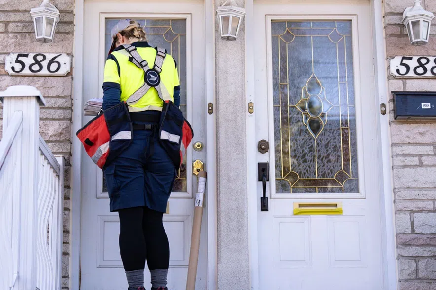 A Canada Post mail carrier delivers a package on their route in Montreal on Wednesday, Nov.13, 2024.