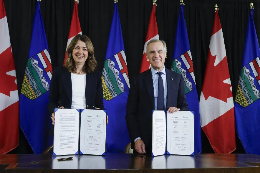 Prime Minister Mark Carney, right, signs an MOU with Alberta Premier Danielle Smith in Calgary, Alta., Thursday, Nov. 27, 2025.