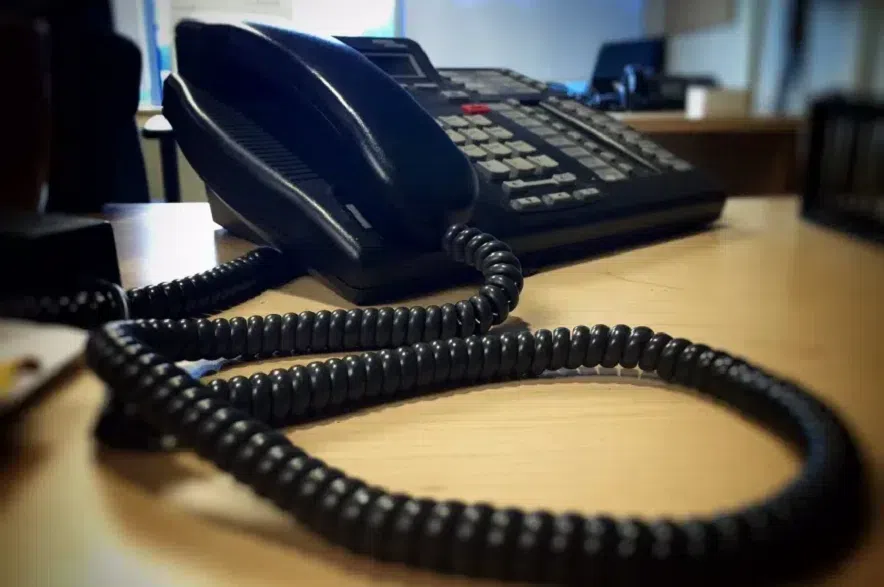 A black telephone sitting on a desk.