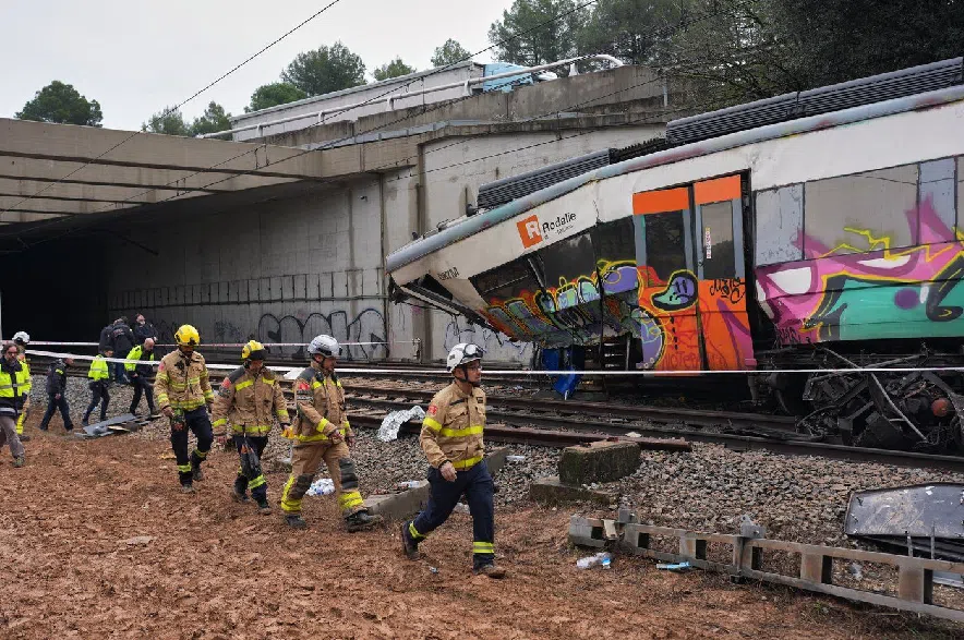 Police officers and firefighters inspect the damage after a commuter train derailed as a retaining wall collapsed onto the tracks in Gelida, near Barcelona, Spain, Wednesday, Jan. 21, 2026.