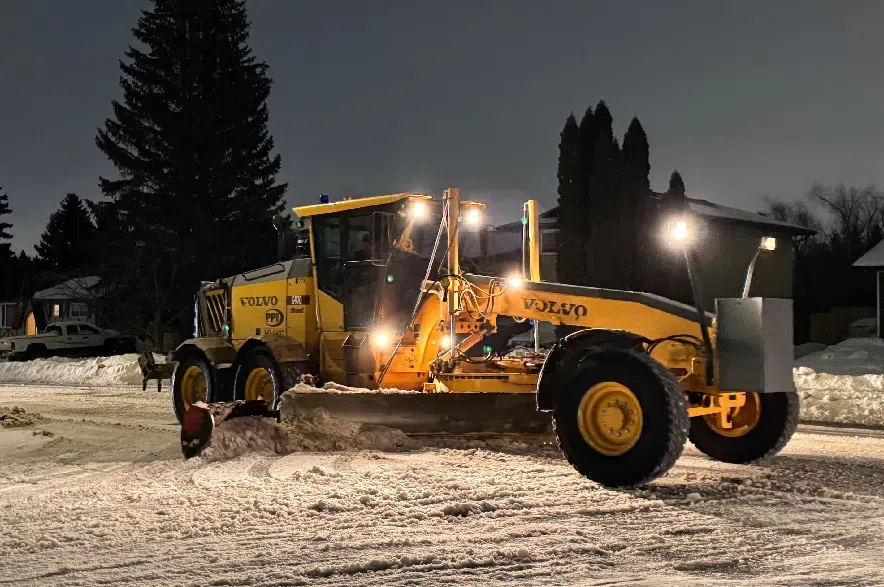 A grader moves snow on a residential street in Saskatoon.