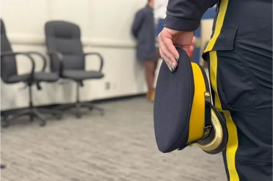Police officer holds hat at side.