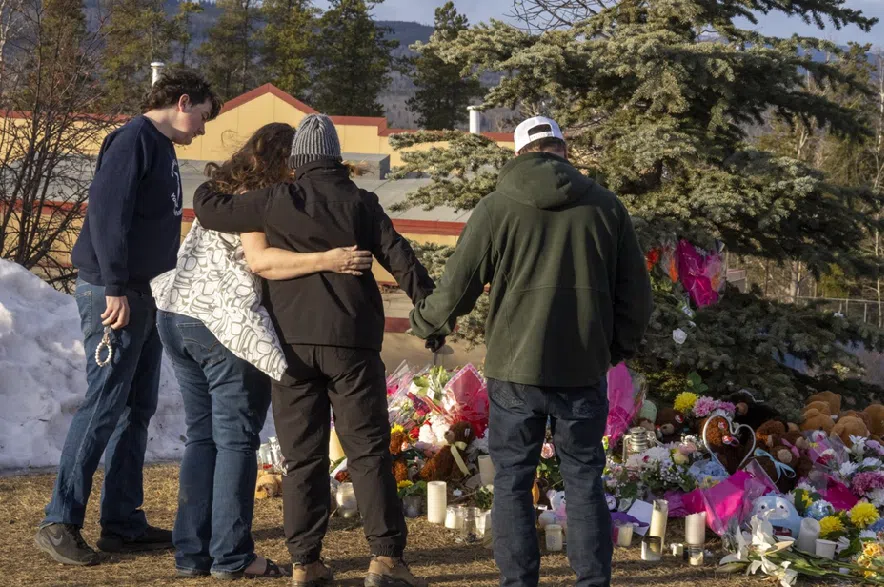 Residents hug as they place flowers at a memorial for the victims of a mass shooting in Tumbler Ridge, B.C., on Thursday, Feb. 12, 2026.