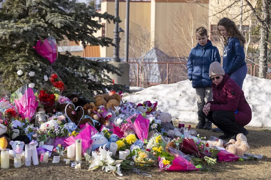 A family pays their respects at a memorial for the victims of a mass shooting in Tumbler Ridge, B.C., on Thursday, Feb. 12, 2026.
