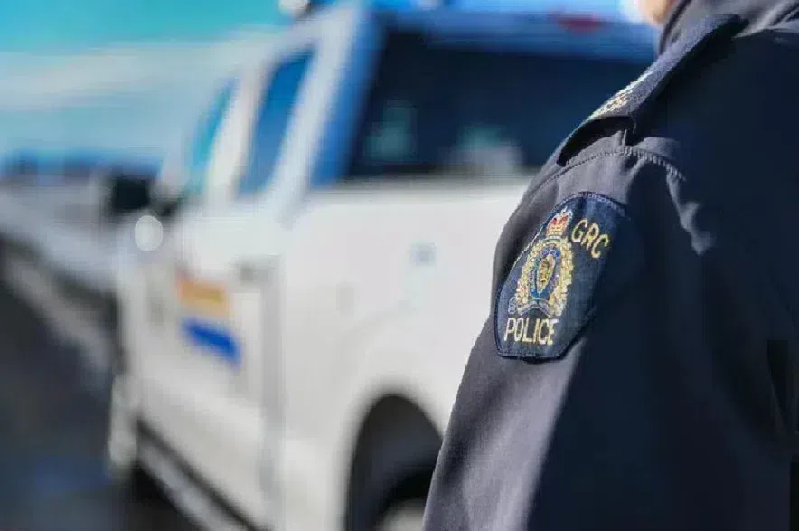 An RCMP officer standing next to a truck on the side of a highway.