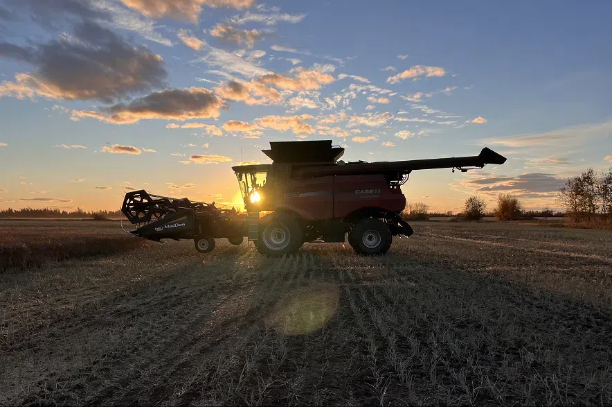 A combine harvester in a Saskatchewan field, silhouetted against the sun.
