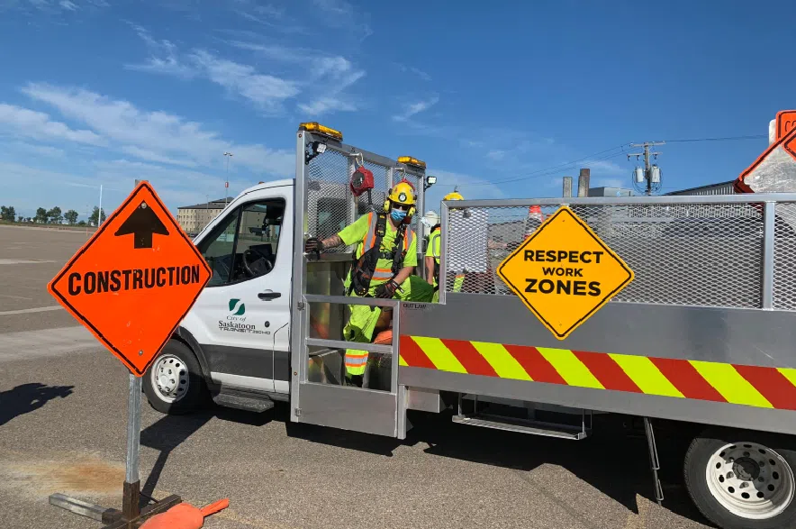 A construction worker wearing safety gear jumping out of a City of Saskatoon vehicle.