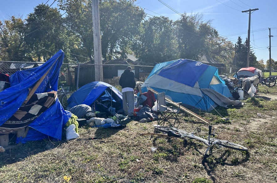 Jason stands beside his blue tent that he said was "messy" on Sept. 24, 2026. He expressed desire to address his mental health worries, then find stable housing before having to spend a seventh winter outside. (Libby Gray/650 CKOM)