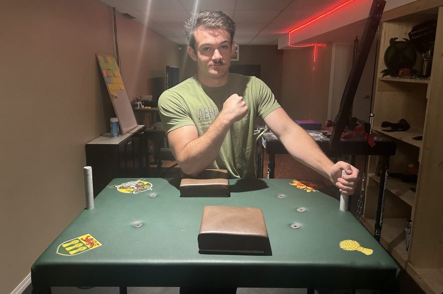 Nathan Muir sits at an arm wrestling table.