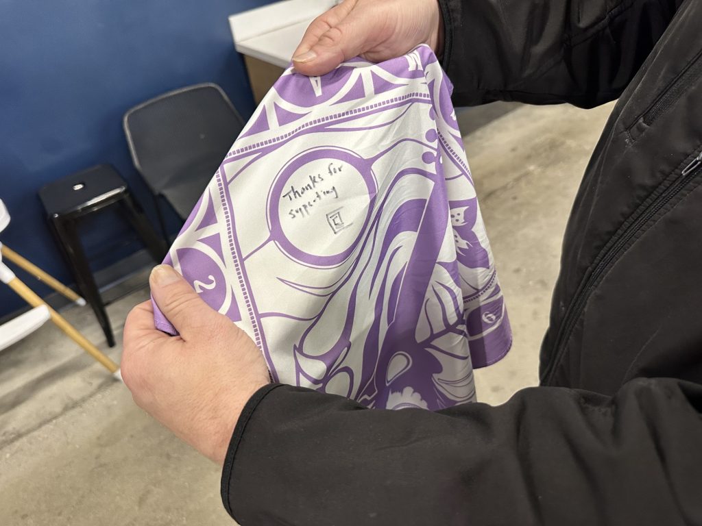 A fan of Chipak's designs holds up his bandana after asking for the artist's signature at Gather Local Market on Sept. 15, 2026. (Libby Gray/650 CKOM)