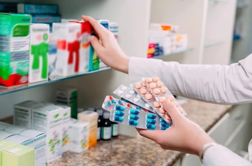 A pharmacist restocks drugs in a pharmacy drugstore.