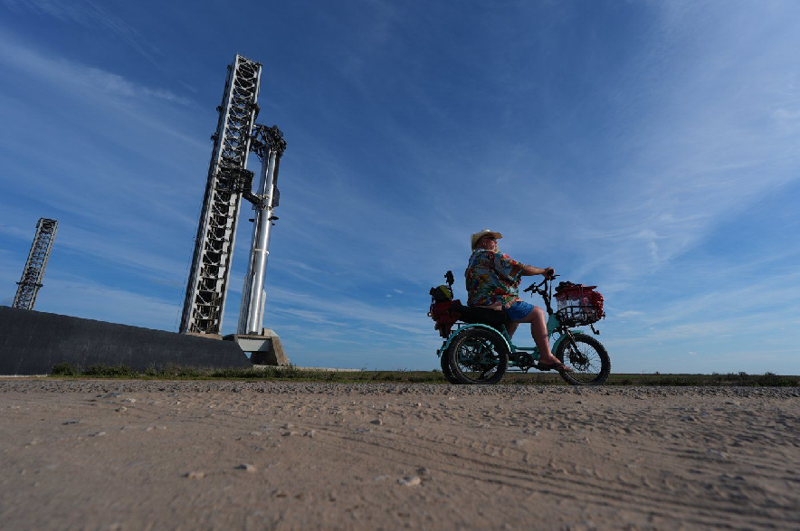 David Orr rides his bike past SpaceX's mega rocket Starship as it is prepared for a test flight from Starbase, Texas, Sunday, Sept. 27, 2026.