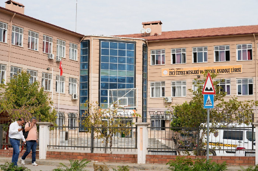 People walk past a vocational and technical high school in the Turgutlu district of Manisa province, western Turkey, Tuesday, Sept. 22, 2026, after a gunman opened fire near the school.