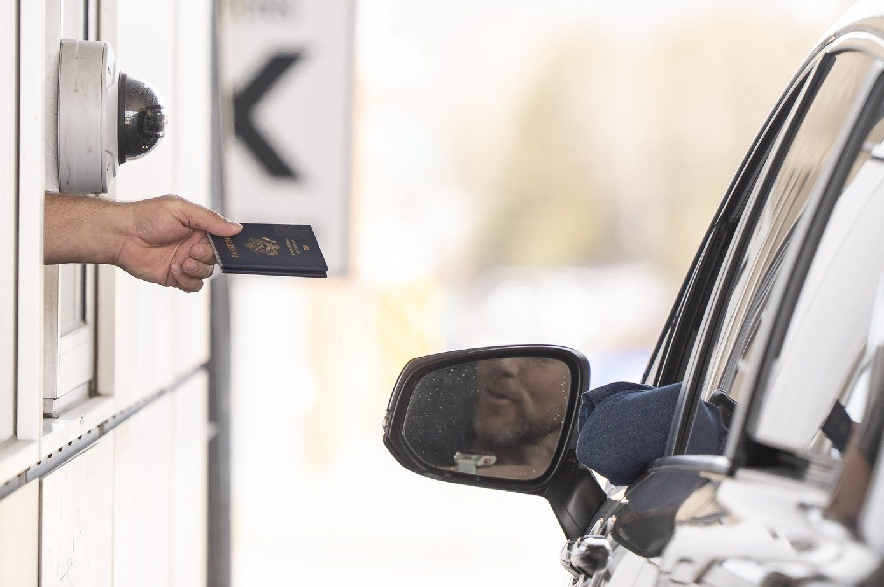 A Canada Border Services officer hands passports back to a visitor entering Canada from Vermont at the Highway 55 Port of Entry in Stanstead, Que., on Thursday, March 13, 2025. On June 11, the U.S. Department of State reissued its travel advisory for Canada, keeping a 'level one' rating, the lowest advisory level for safety and security risk.