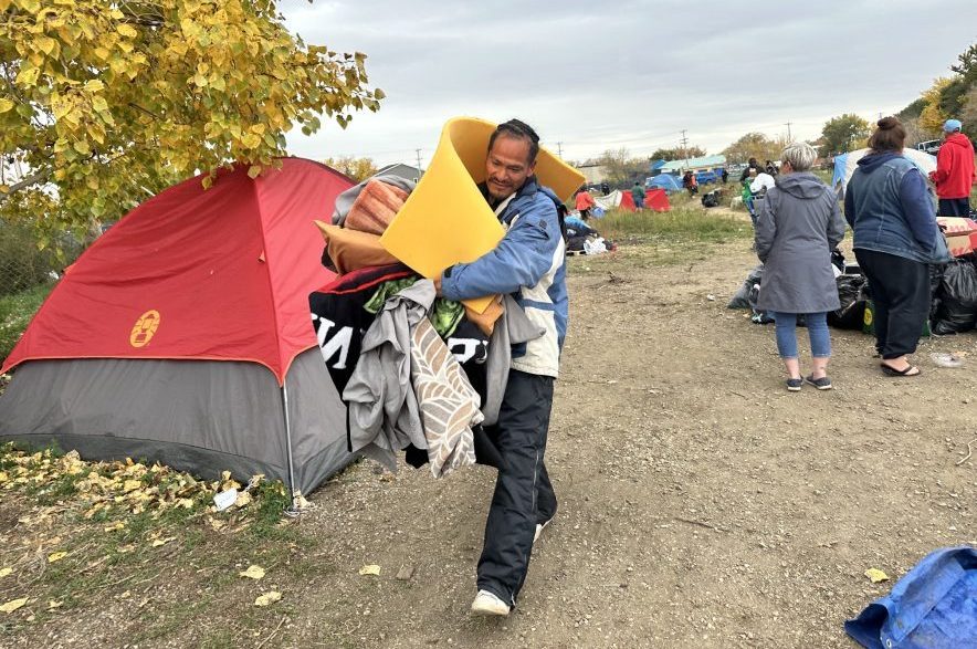 A resident at the Saskatoon encampment carries loads of his belongings out of the encampment on Oct. 8, 2026. (Libby Gray/650 CKOM)