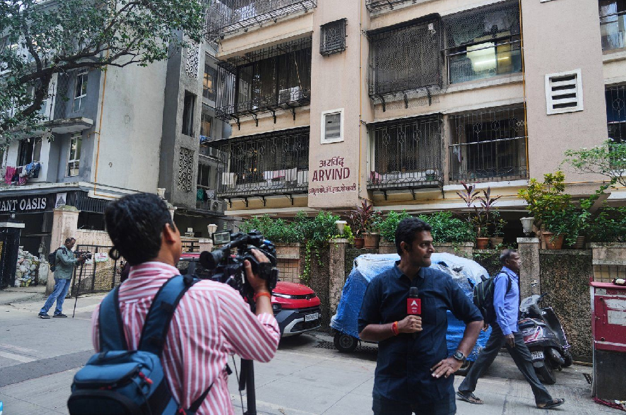 News media personnel stand outside the building where relatives of Smit Machchhar, an Indian pilot for Flydubai, previously lived in Mumbai, India, Thursday, Oct. 1, 2026.