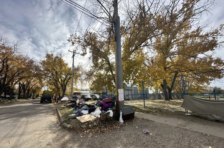 Outside the encampment across the street from Station 20 West, along Avenue K, tents and belongings take up most of the curb space on Oct. 9, 2026. (Libby Gray/650 CKOM)