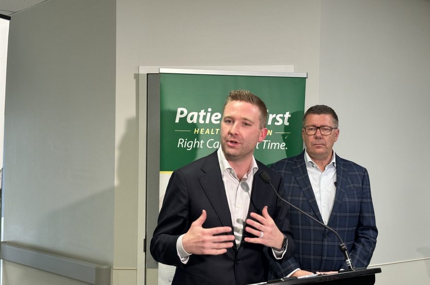 Saskatchewan Minister of Health Jeremy Cockrill speaks to reporters at Saskatoon City Hospital on Oct. 20, 2026, with Premier Scott Moe standing behind him. (Libby Gray/650 CKOM)