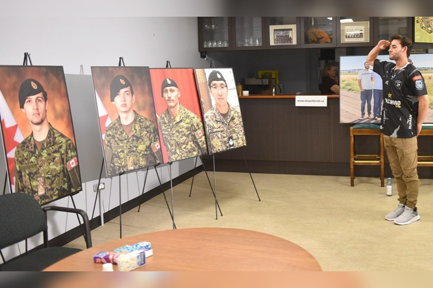 Byron Farrell salutes images of his brother Shaun Farrell and his three fallen comrades.